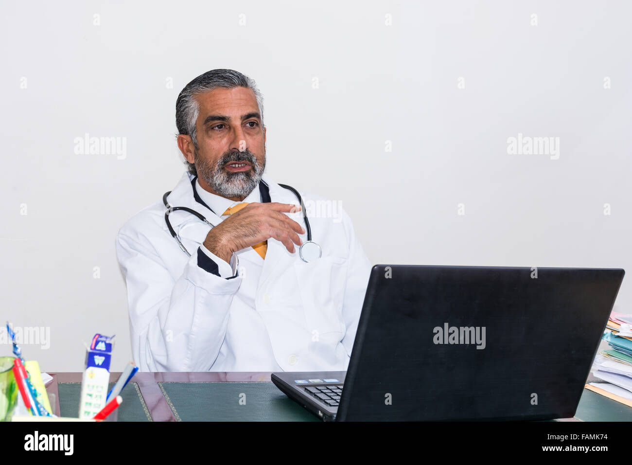 El doctor usa el portátil en su estudio. Incluso médicos y medicamentos, al igual que otros profesionales, utilizar las nuevas tecnologías, como un ordenador portátil. Foto de stock