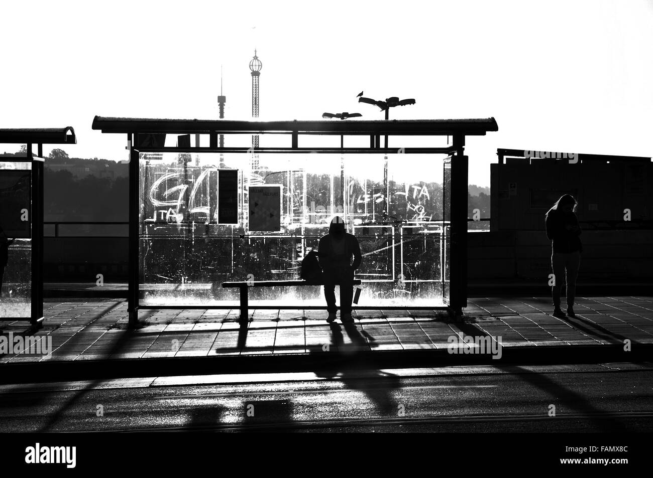 La fotografía de la calle de alguien esperando en una parada de autobús en blanco y negro. Foto de stock