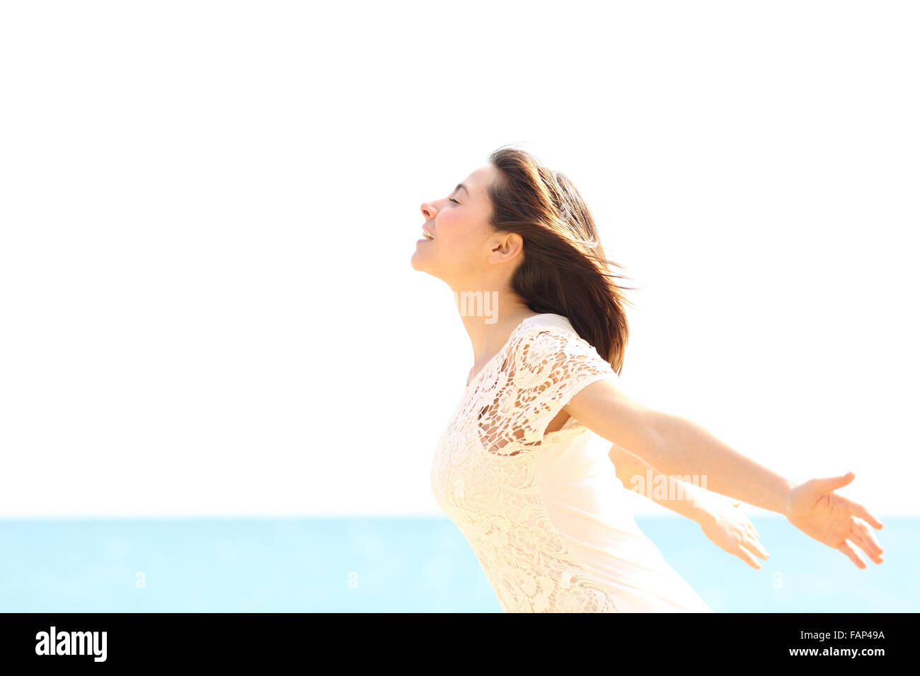 Mujer alegre y disfrutando del viento y respirar aire fresco en la playa en un día soleado y ventoso Foto de stock