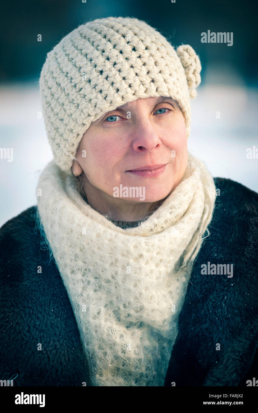 Un invierno retrato de una mujer adulta senior llevar gorro de lana y una bufanda, con un fondo de nieve Foto de stock