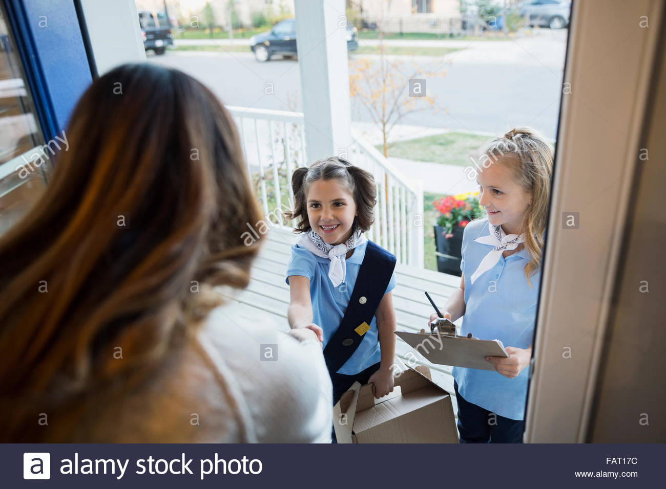 Girl Scouts vendiendo cookies mujer en puerta frontal Foto de stock