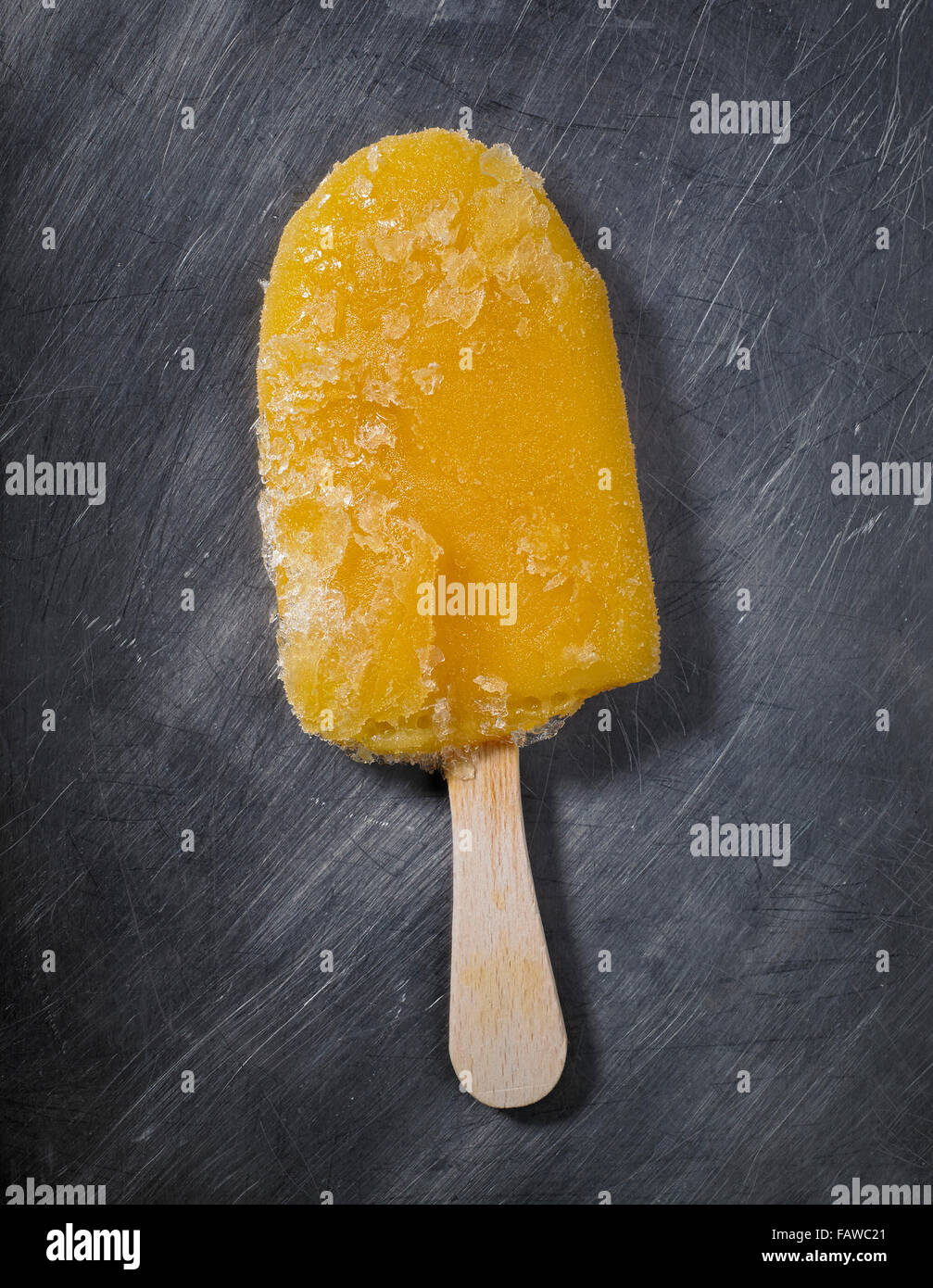 Los cristales de hielo en una máquina de paleta de helado de naranja colocado sobre un fondo de color gris acero, gris Foto de stock