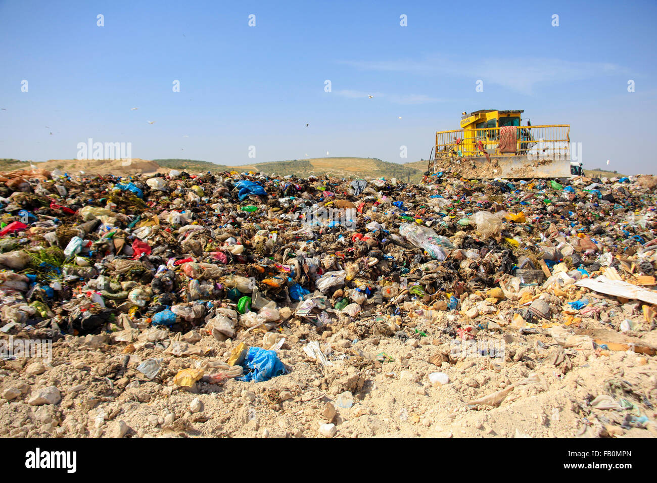 Una topadora está disponiendo los residuos sólidos para un vertedero en Palestina Foto de stock