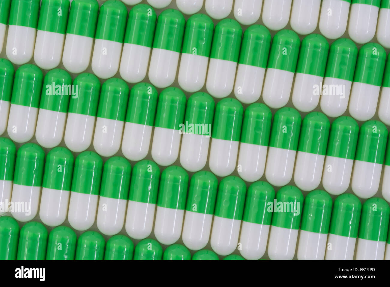 Primer plano de pastillas - forma de cápsula hecha de gelatina. Pastillas verdes / blancas. Metáfora tomando a las compañías farmacéuticas estadounidenses sobre los altos precios de los medicamentos, ensayos de drogas. Foto de stock