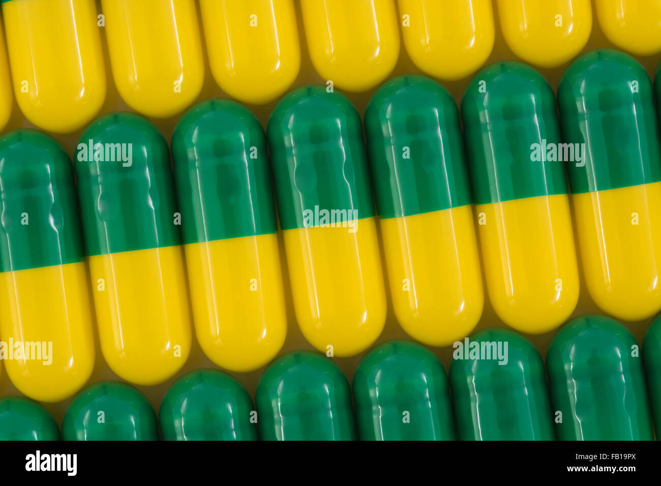 Primer plano de pastillas - forma de cápsula hecha de gelatina. Pastillas verdes / amarillas. Metáfora tomando a las compañías farmacéuticas estadounidenses sobre los altos precios de los medicamentos, ensayos de drogas. Foto de stock