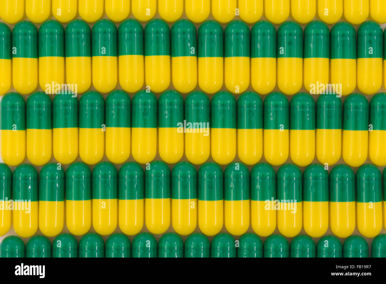 Primer plano de pastillas - forma de cápsula hecha de gelatina. Pastillas verdes / amarillas. Metáfora tomando a las compañías farmacéuticas estadounidenses sobre los altos precios de los medicamentos, ensayos de drogas. Foto de stock
