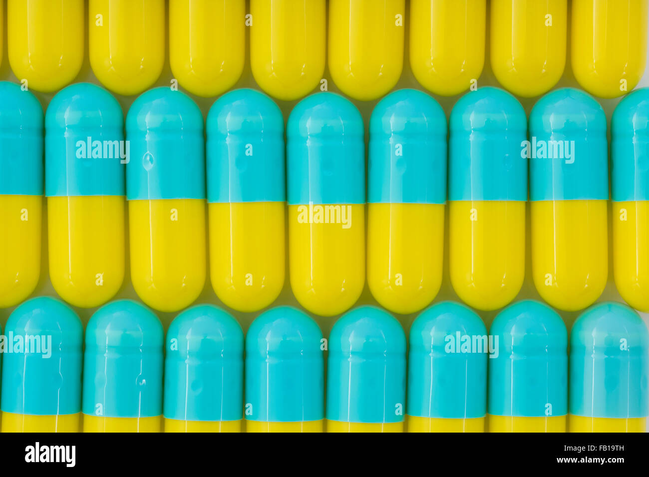 Primer plano de pastillas - forma de cápsula hecha de gelatina.Amarillo / Azul pastillas. Metáfora tomando a las compañías farmacéuticas estadounidenses sobre los altos precios de los medicamentos, ensayos de drogas. Foto de stock