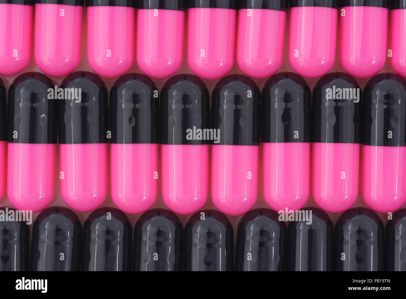 Primer plano de pastillas - forma de cápsula hecha de gelatina. Pastillas rosadas y negras. Metáfora tomando a las compañías farmacéuticas estadounidenses sobre los altos precios de los medicamentos, ensayos de drogas. Foto de stock