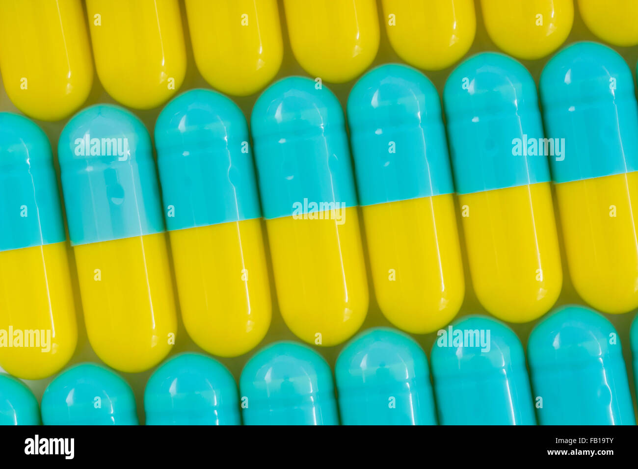 Primer plano de pastillas - forma de cápsula hecha de gelatina. Pastillas amarillas / azules. Metáfora tomando a las compañías farmacéuticas estadounidenses sobre los altos precios de los medicamentos, ensayos de drogas. Foto de stock