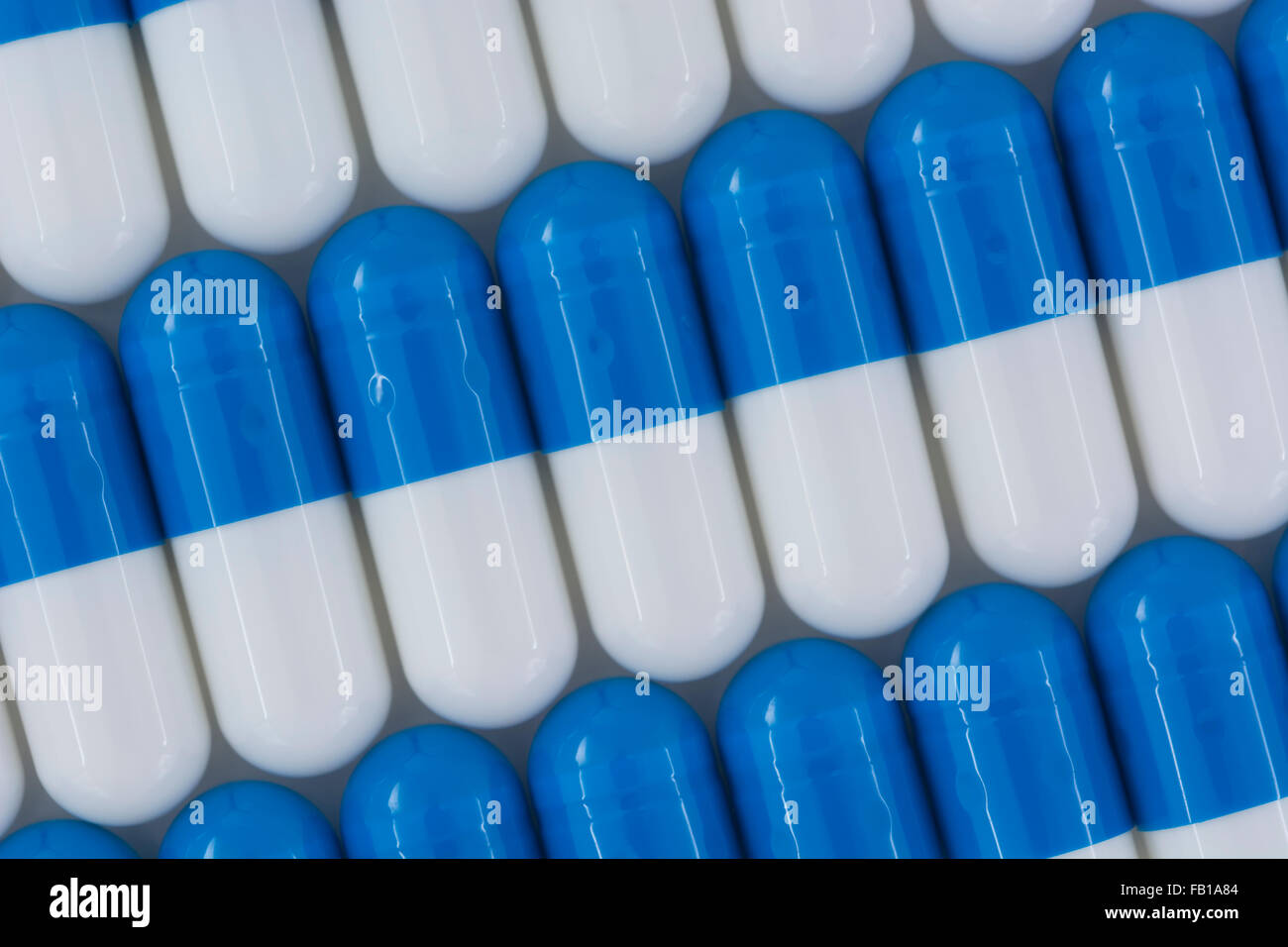 Primer plano de pastillas azules y blancas - forma de cápsula hecha de gelatina. Metáfora tomando a las compañías farmacéuticas estadounidenses sobre los altos precios de los medicamentos, ensayos de drogas. Foto de stock