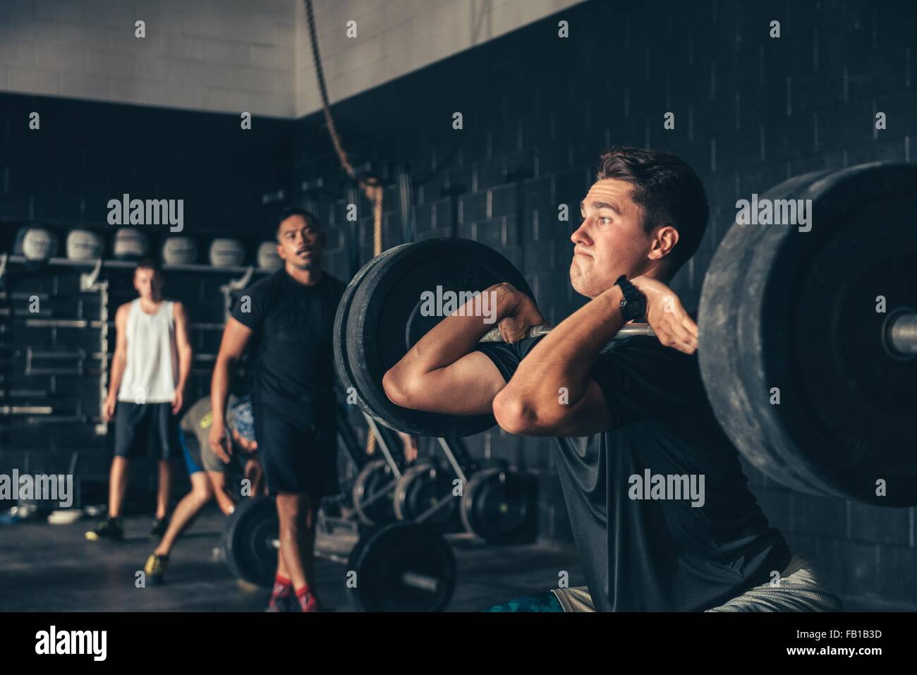 Hombre y entrenamiento con barbell en gimnasio Foto de stock