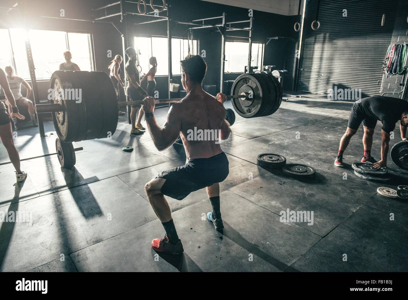 Hombre con formación barbell en gimnasio Foto de stock