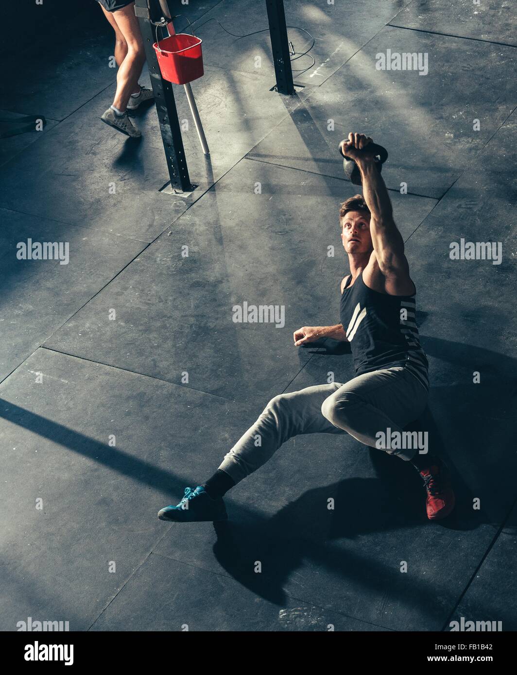 Un alto ángulo de visión del hombre entrenamiento con kettlebell en gimnasio Foto de stock