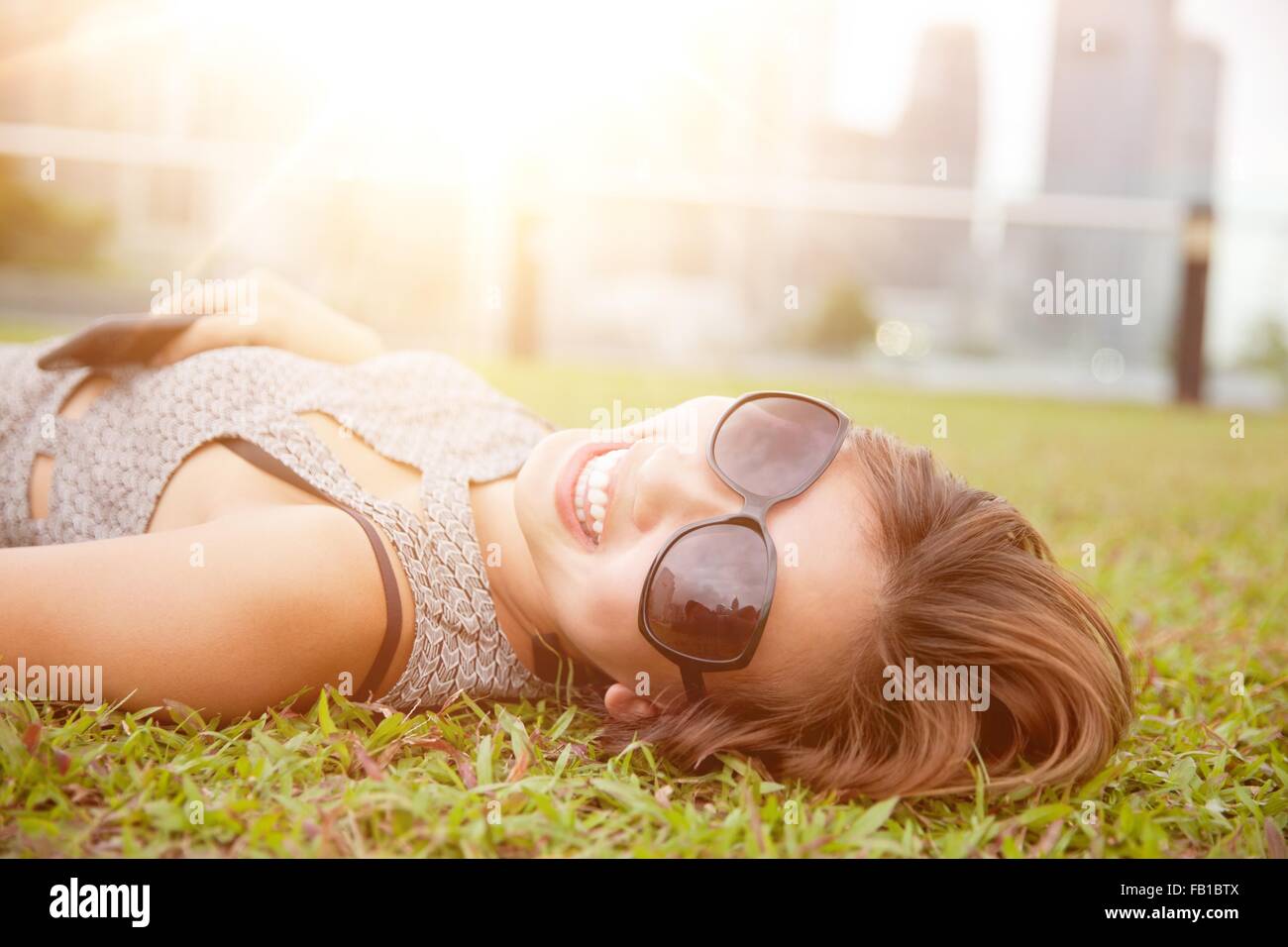 Retrato de mujer joven acostado en el pasto, sonriendo Foto de stock