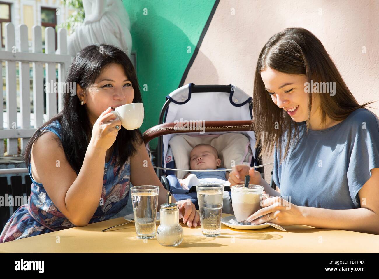 Mujer joven con la madre y la hija de beber café en la cafetería Foto de stock
