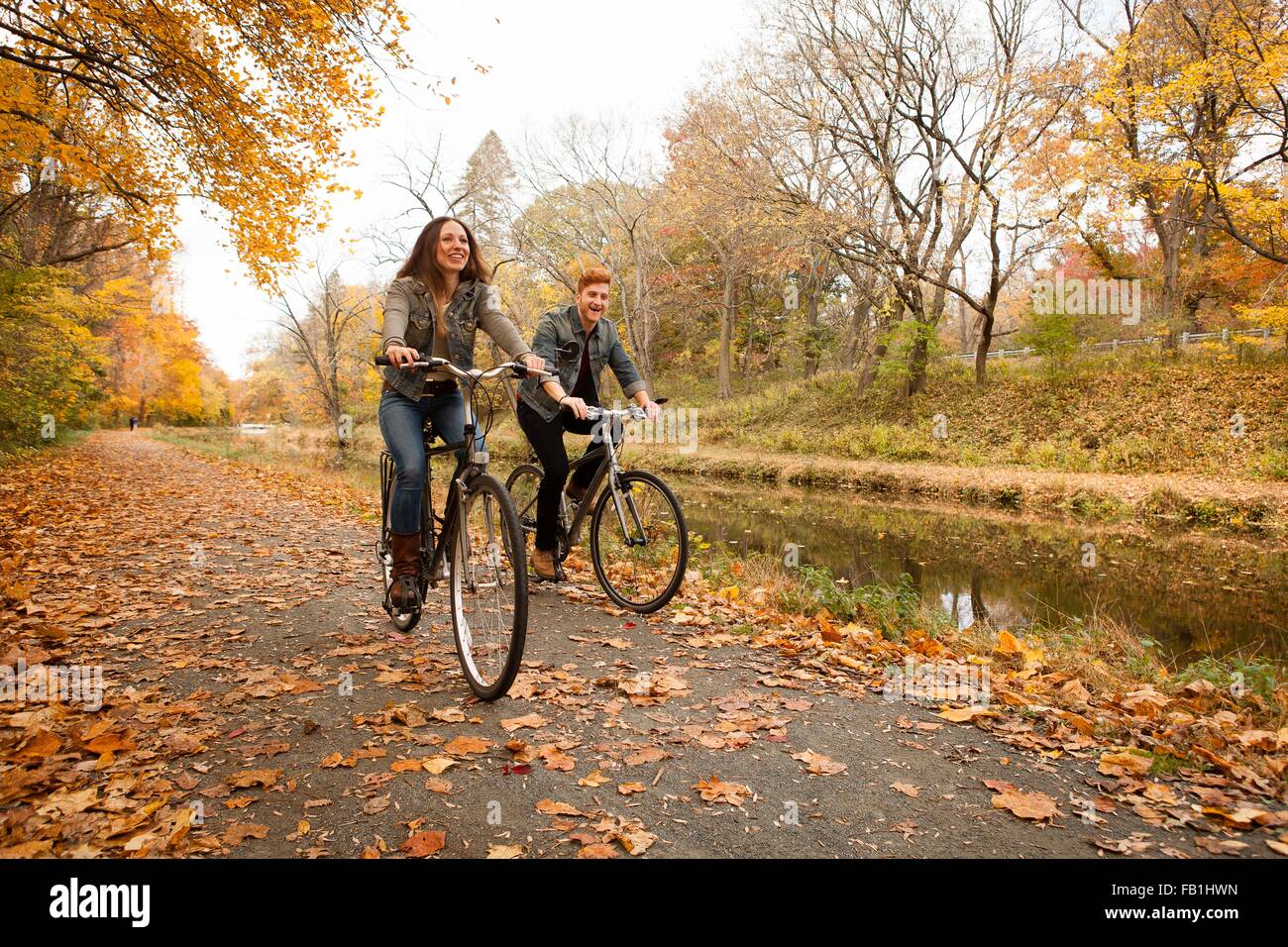 Feliz pareja joven en bicicleta a lo largo de Riverside en otoño Foto de stock