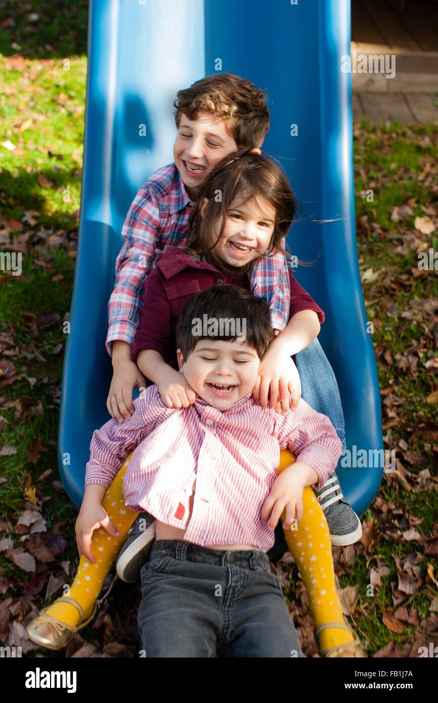 Los hermanos en una fila entre otras piernas en playground deslice  sonriendo Fotografía de stock - Alamy