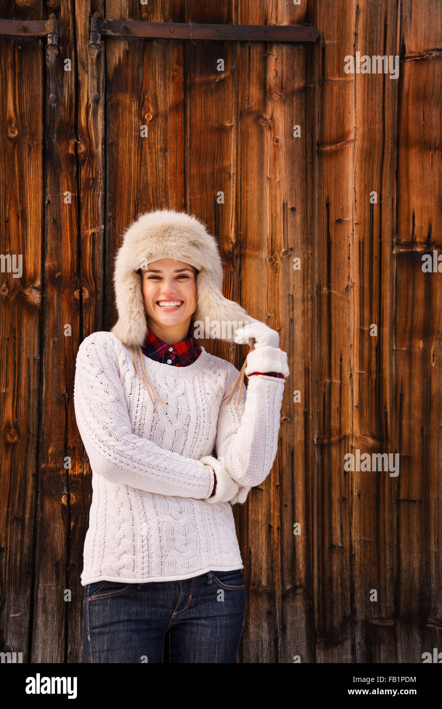 Invierno en el estilo country. Mujer sonriente en blanco y suéter tejido  peludo sombrero en la parte frontal de la pared de madera rústica  Fotografía de stock - Alamy
