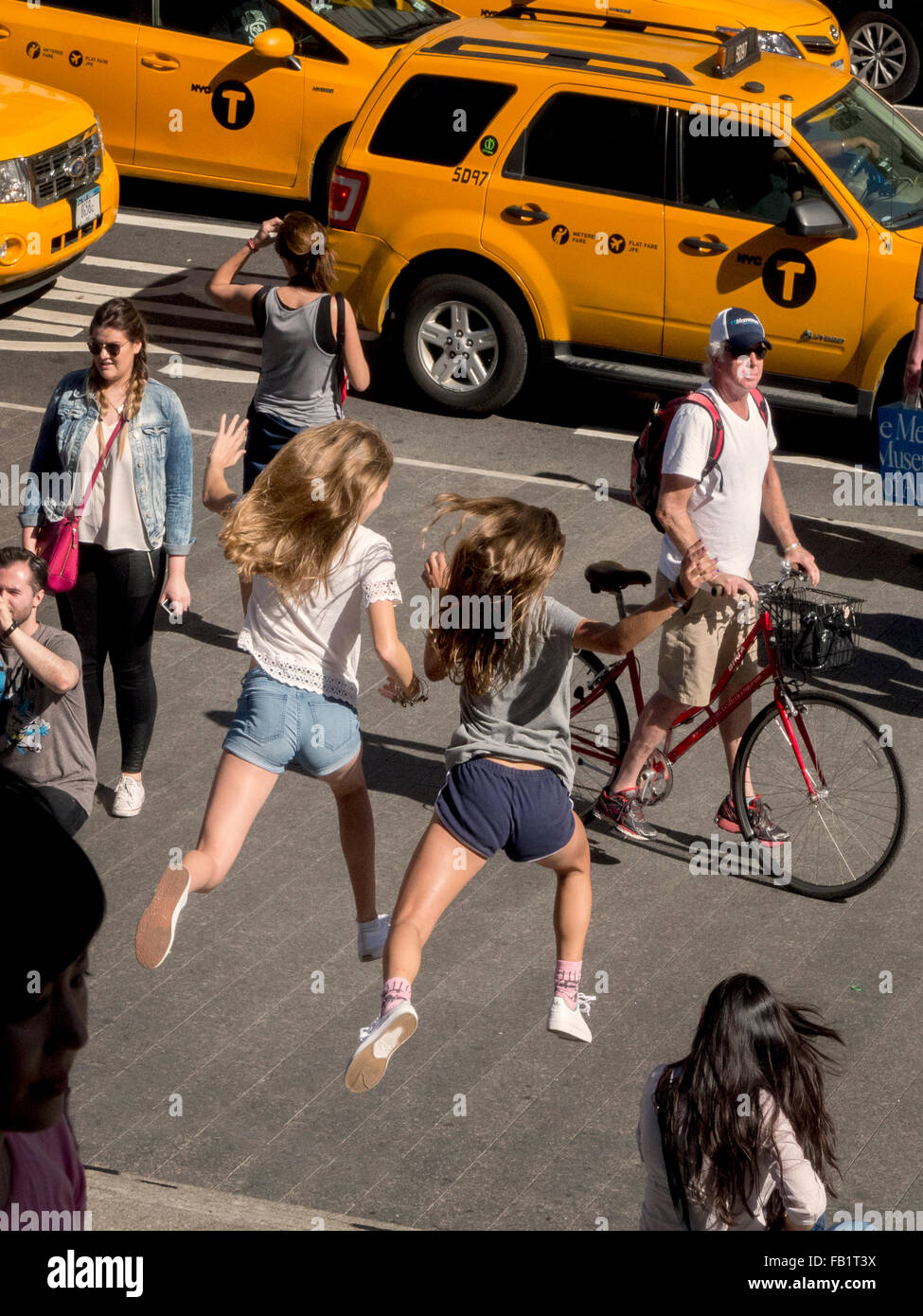 Dos chicas adolescentes exuberante saltar los pasos de la ciudad de Nueva York el Metropolitan Museum of Art de la Quinta Avenida. Nota taxis y peatones. Foto de stock