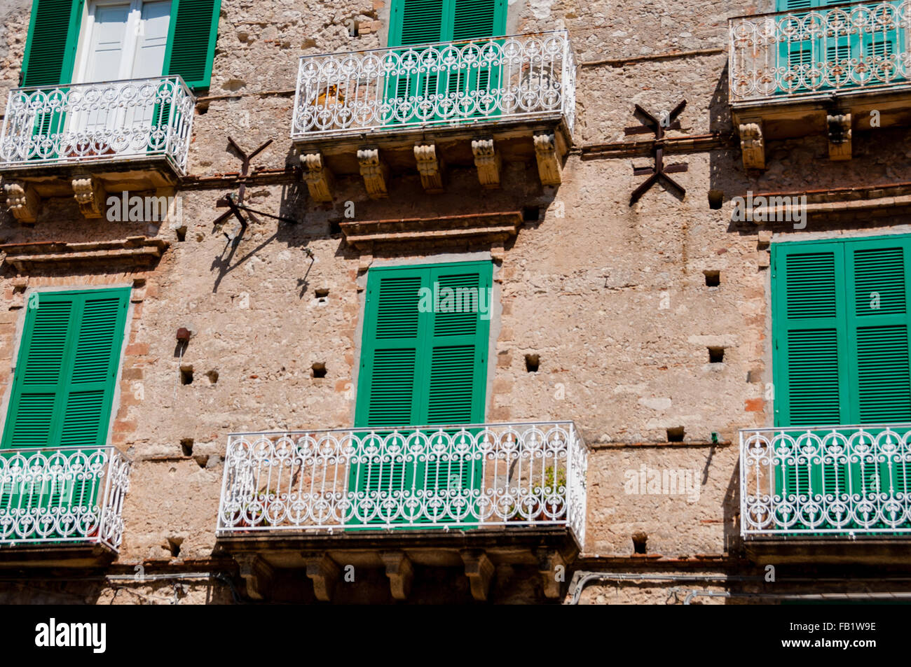 Antigua casa de piedra italiana frente con persianas de obturador verde y balcón en Tropea Foto de stock