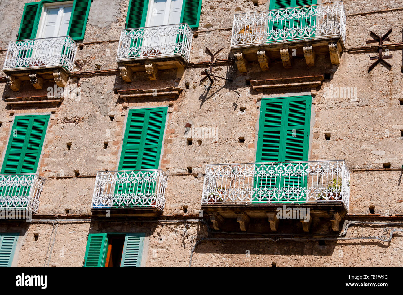 Casa de piedra italiana frente con persianas de obturador verde y balcón en Tropea Foto de stock