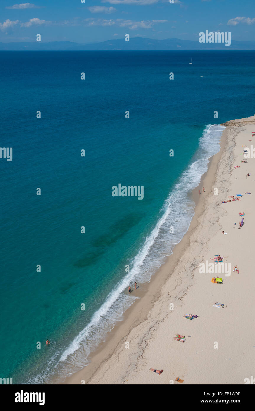 Amarillo arena limpia playa con gente tomando el sol junto al mar mediterráneo en la costa de Tropea Foto de stock
