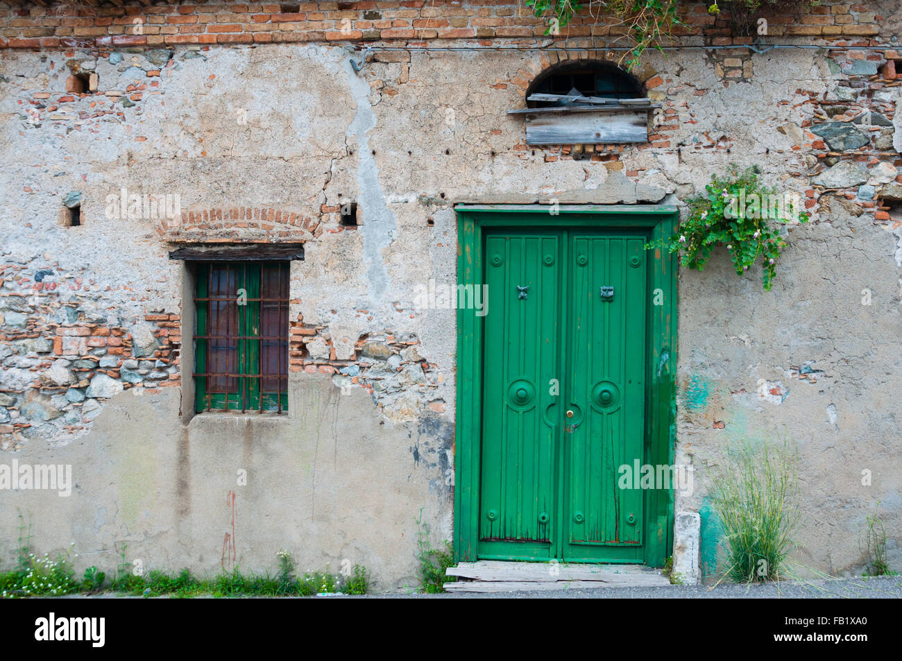 Antigua casa de piedra italiano frontal con puerta verde Foto de stock