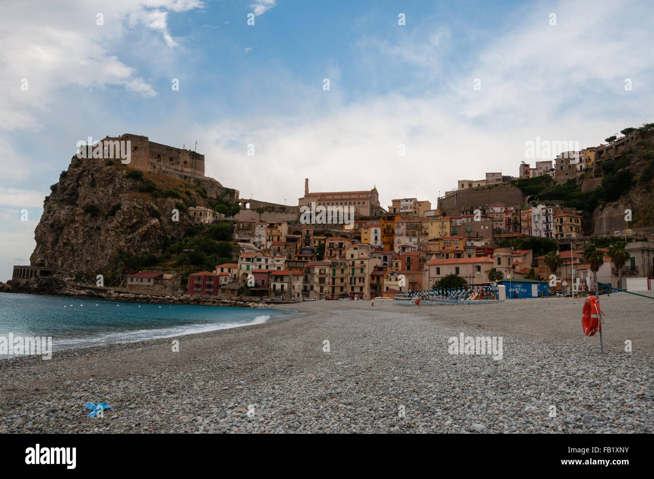 Playa de piedra antigua y pequeña ciudad italiana sobre un acantilado bajo un cielo azul Foto de stock