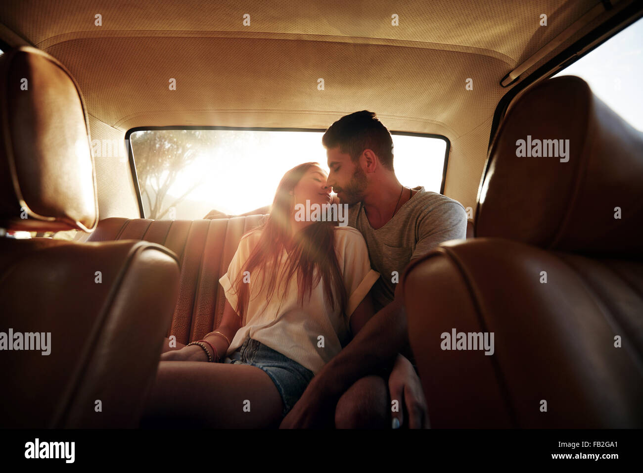Romántica pareja joven en el asiento trasero del coche. Pareja amorosa en viaje por carretera. Foto de stock