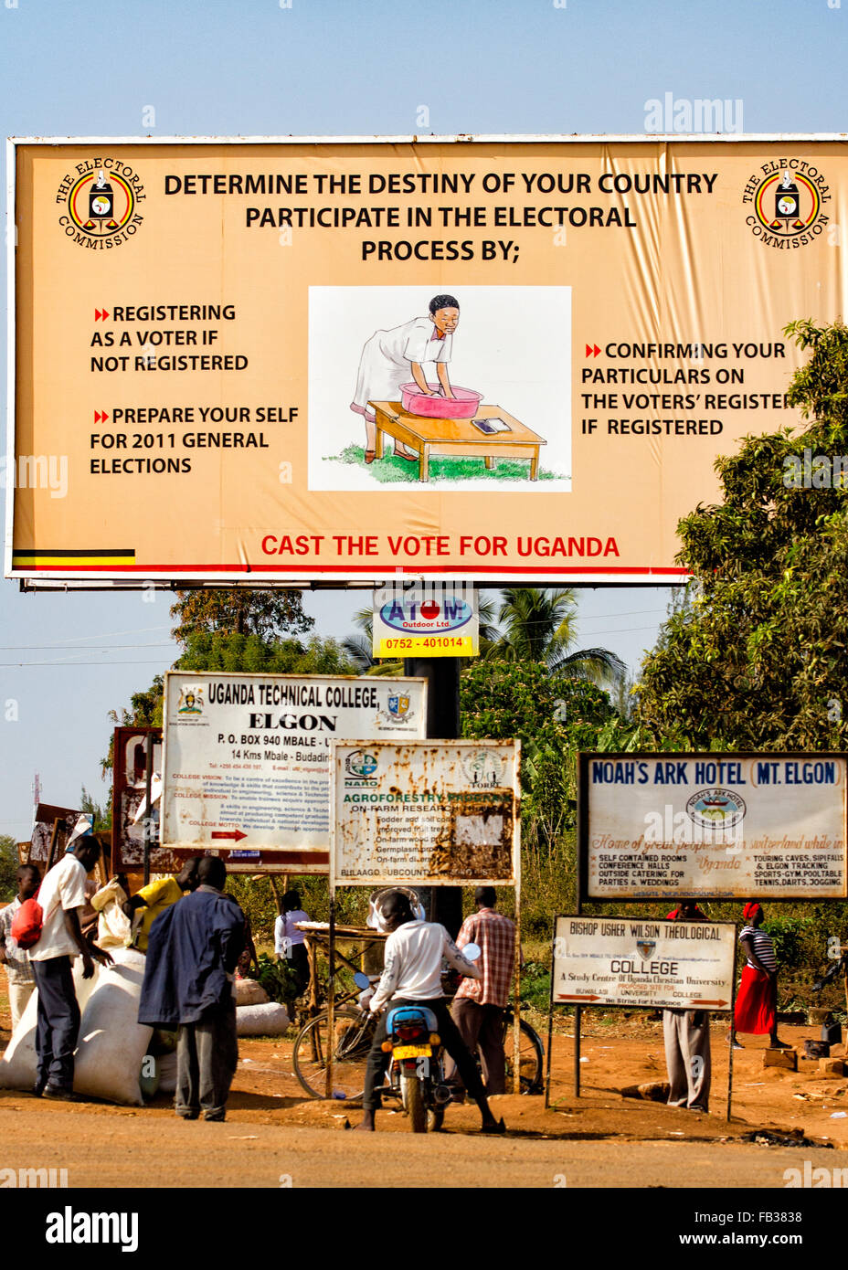 De mbale, Uganda - aldeanos pasando por un cartel exterior ugandés bz emitió la comisión electoral llamando a la participación en el Foto de stock