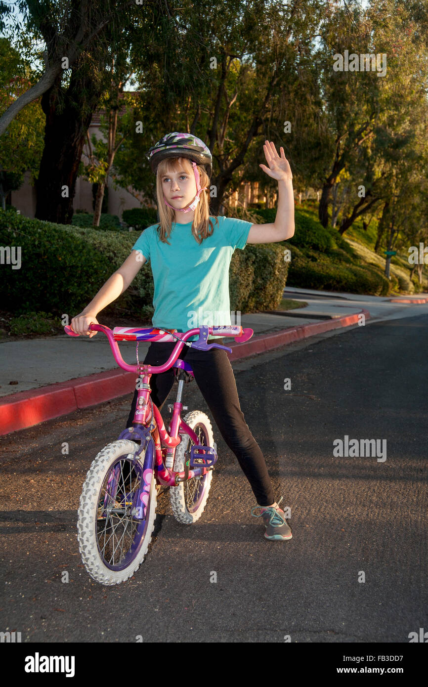 Una interpolación chica ciclista indica un giro a la derecha con su brazo izquierdo en una calle en Lake Forest, CA MODELO DE LIBERACIÓN Foto de stock