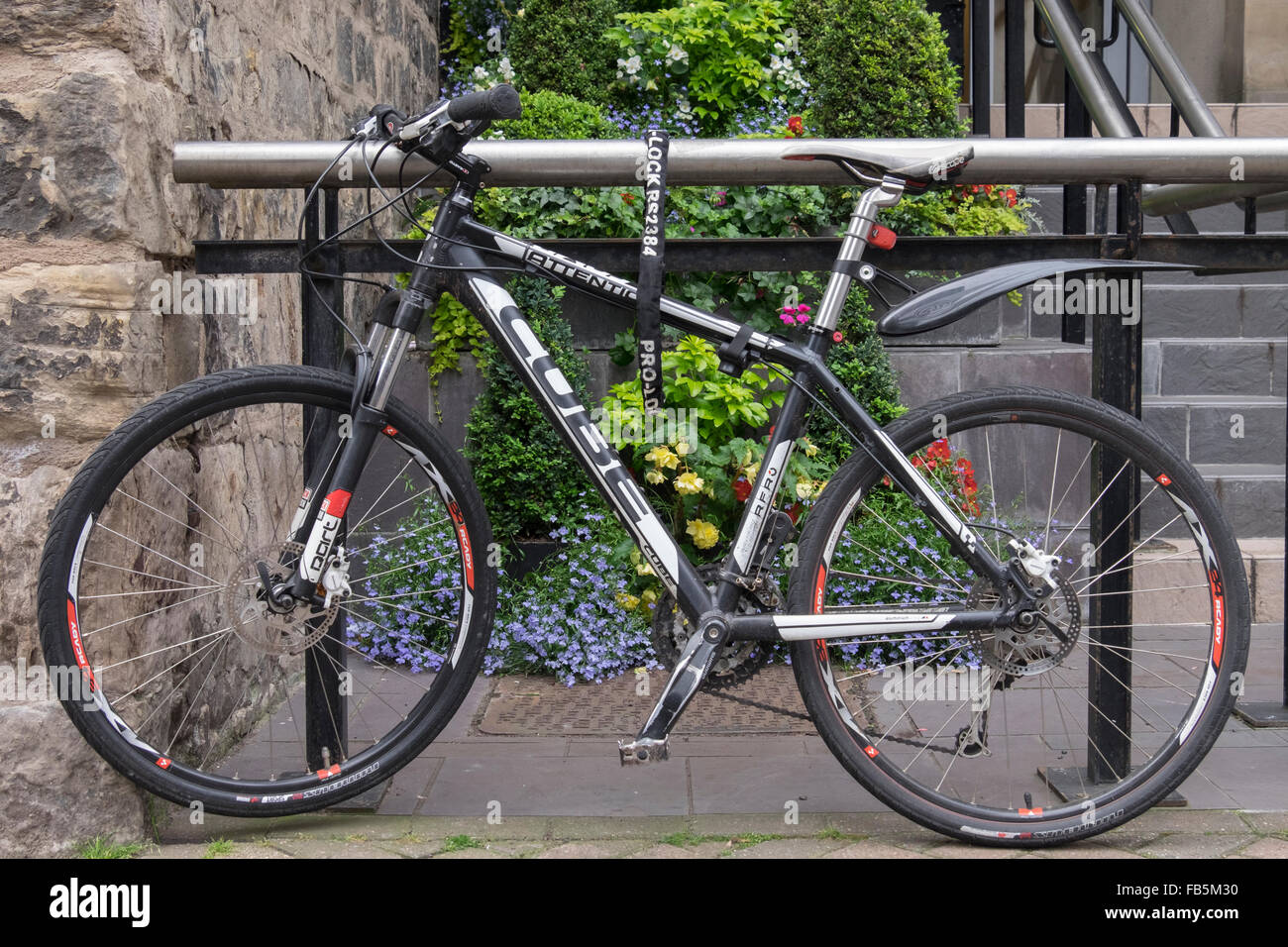 Ciclo de trabajo. Bicicleta bloqueado para barandillas en Rose Street, Edimburgo. Precioso jardín de flores detrás. Foto de stock