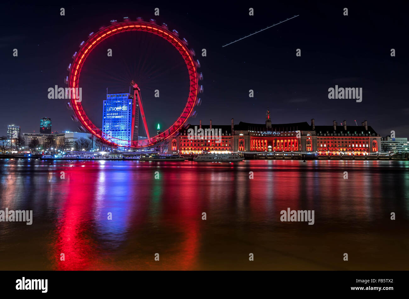 London Eye en la noche y la pista de vuelo en el cielo Foto de stock