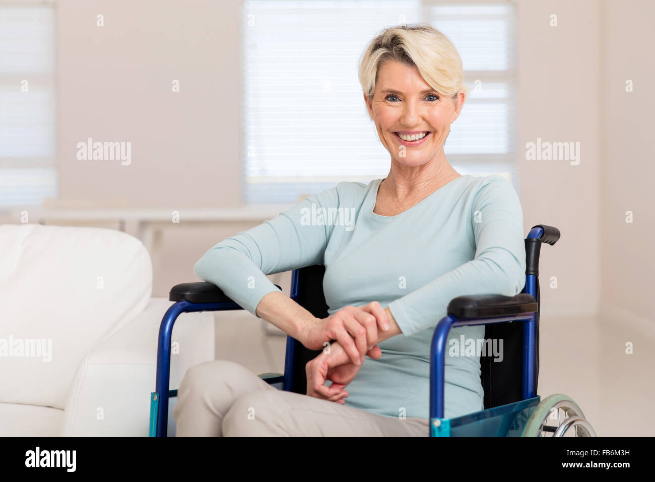 Feliz mujer de mediana edad sentado en la silla de ruedas y recuperarse de la enfermedad Foto de stock