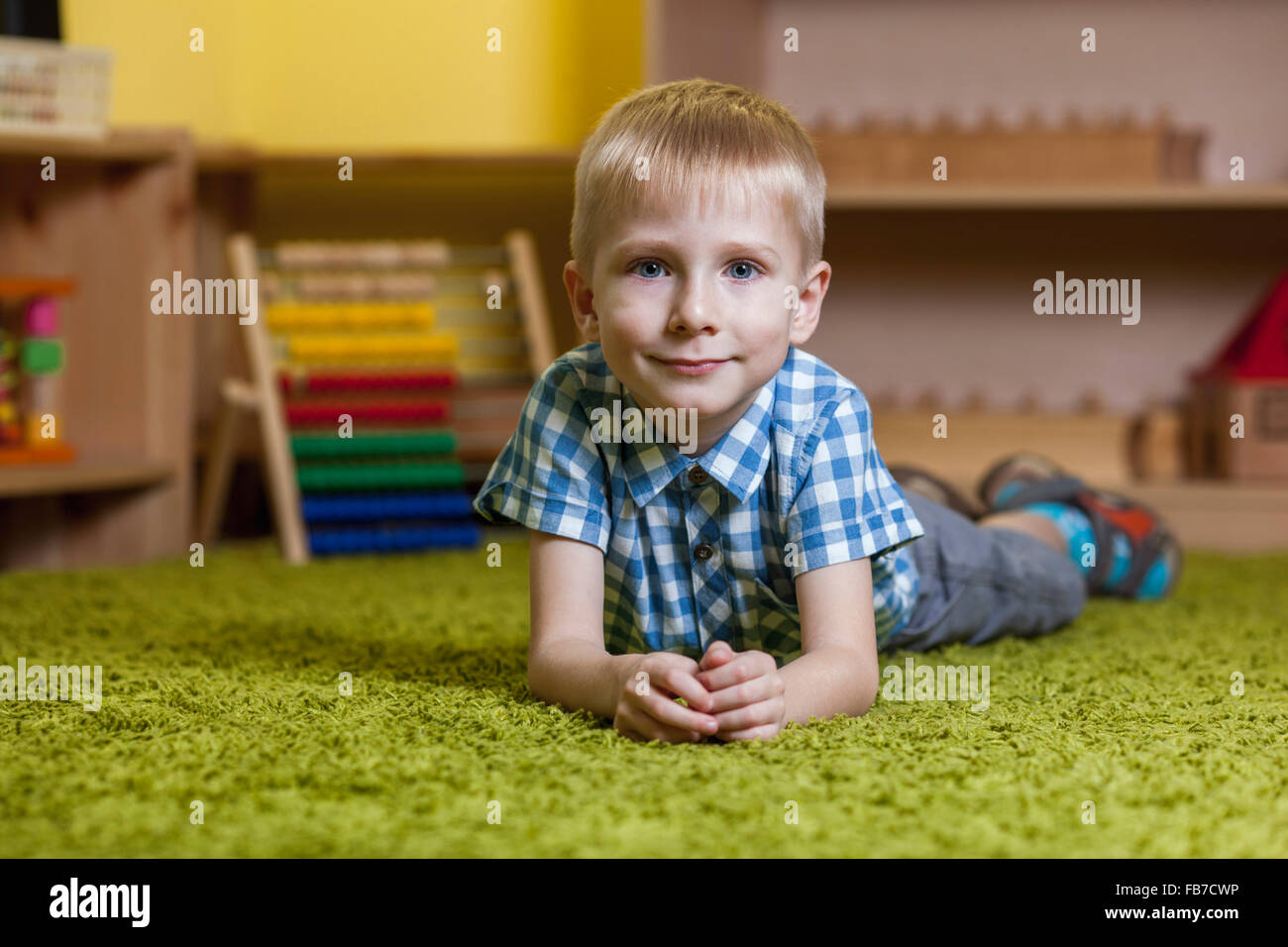 Longitud total Retrato de niño acostado sobre una alfombra en el aula Foto de stock