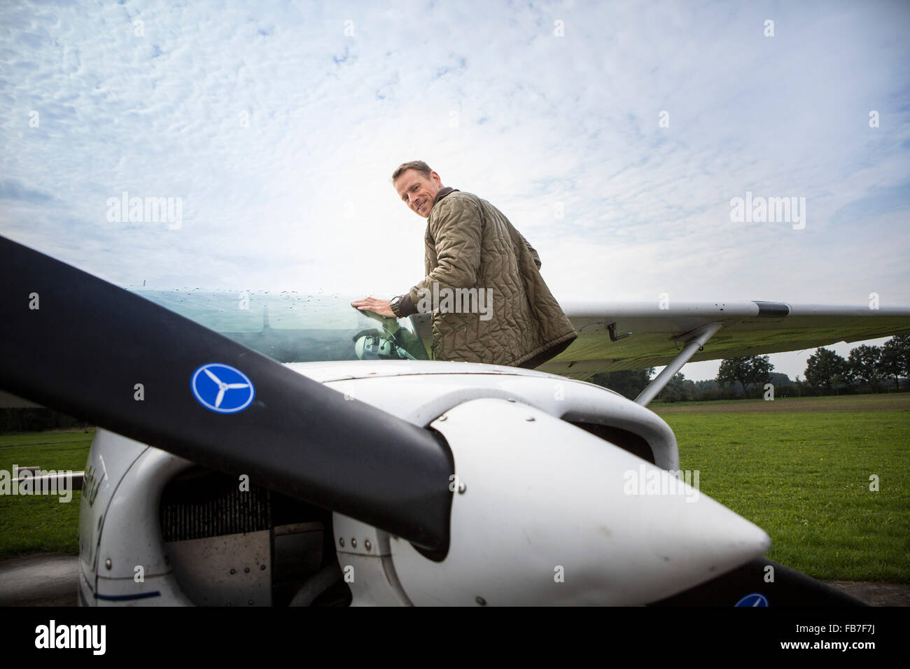 Vista lateral retrato de hombre de pie por avión privado contra el cielo Foto de stock