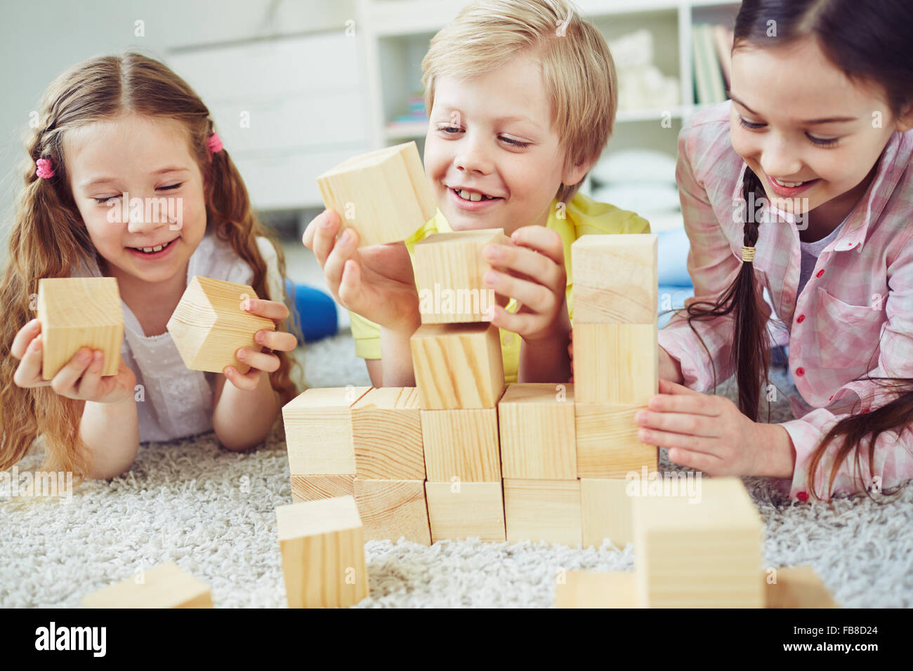 Tres niños jugando con bloques de madera juntos la construcción de torre  Fotografía de stock - Alamy
