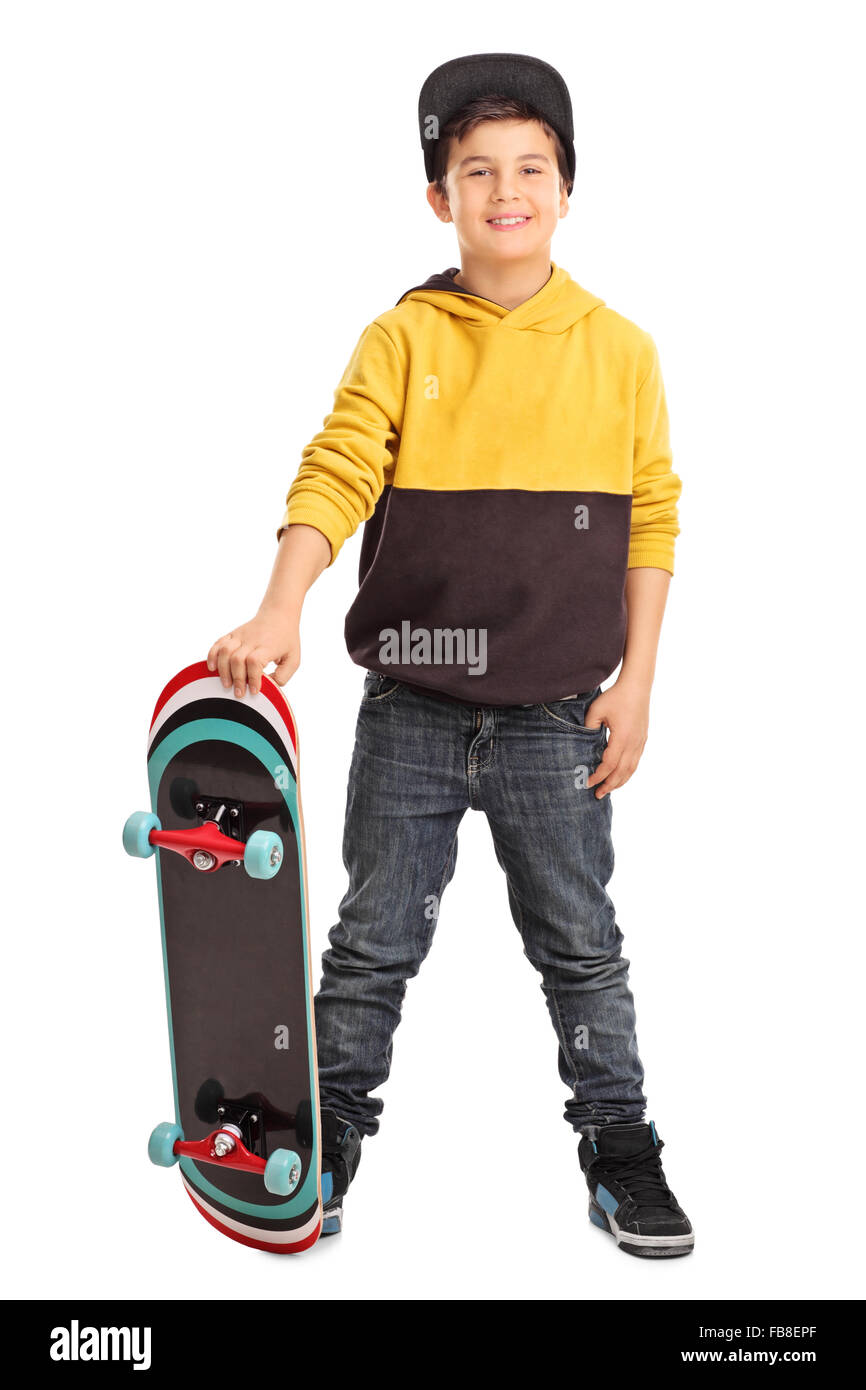 Longitud total retrato de un pequeño y lindo skater niño sosteniendo un monopatín y mirando la cámara aislada sobre fondo blanco. Foto de stock