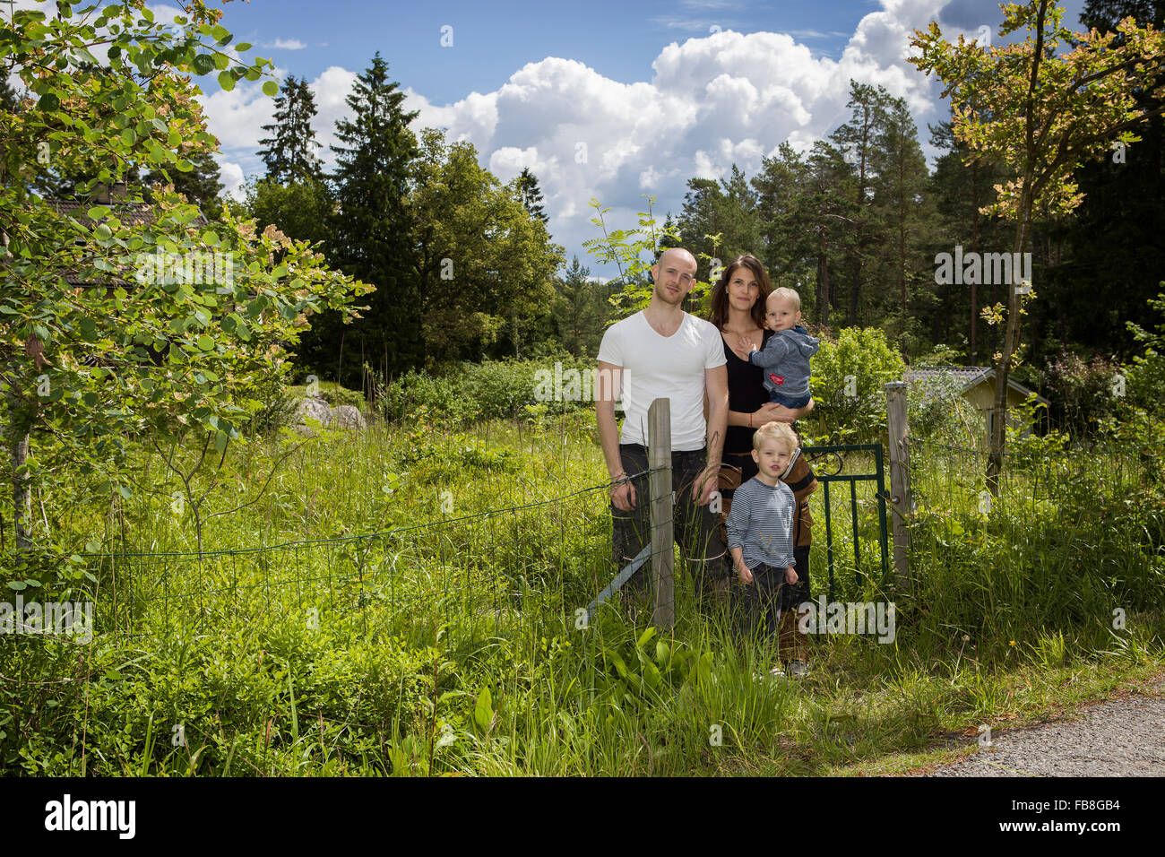 Suecia, Estocolmo, Uppland, Nacka, familia con dos hijos (18-23 meses, 4-5) parado entre un exuberante follaje Foto de stock