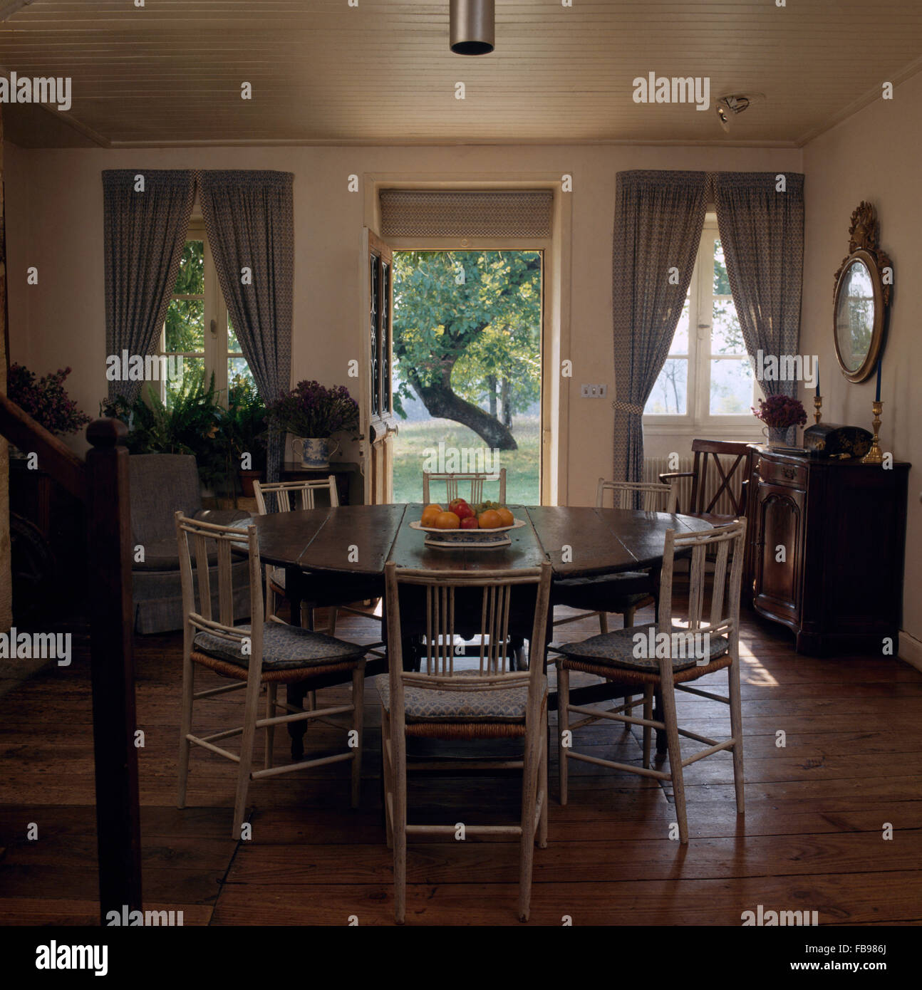 Pintada de color crema, sillas en la mesa circular en el país comedor con pisos de madera Foto de stock