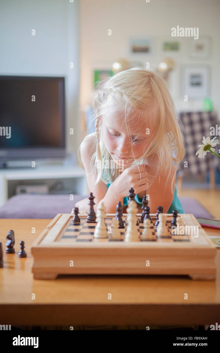 Suecia, Vastergotland, Lerum, Chica (8-9) jugando al ajedrez en el salón Foto de stock