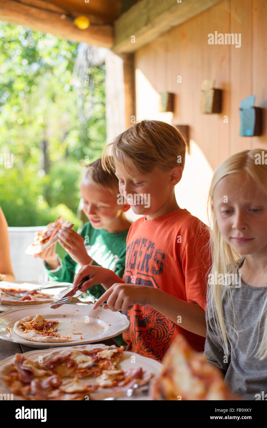 Suecia, Skane (8-9), a los hermanos y hermanas (10-11) comer pizza en la cena familiar. Foto de stock