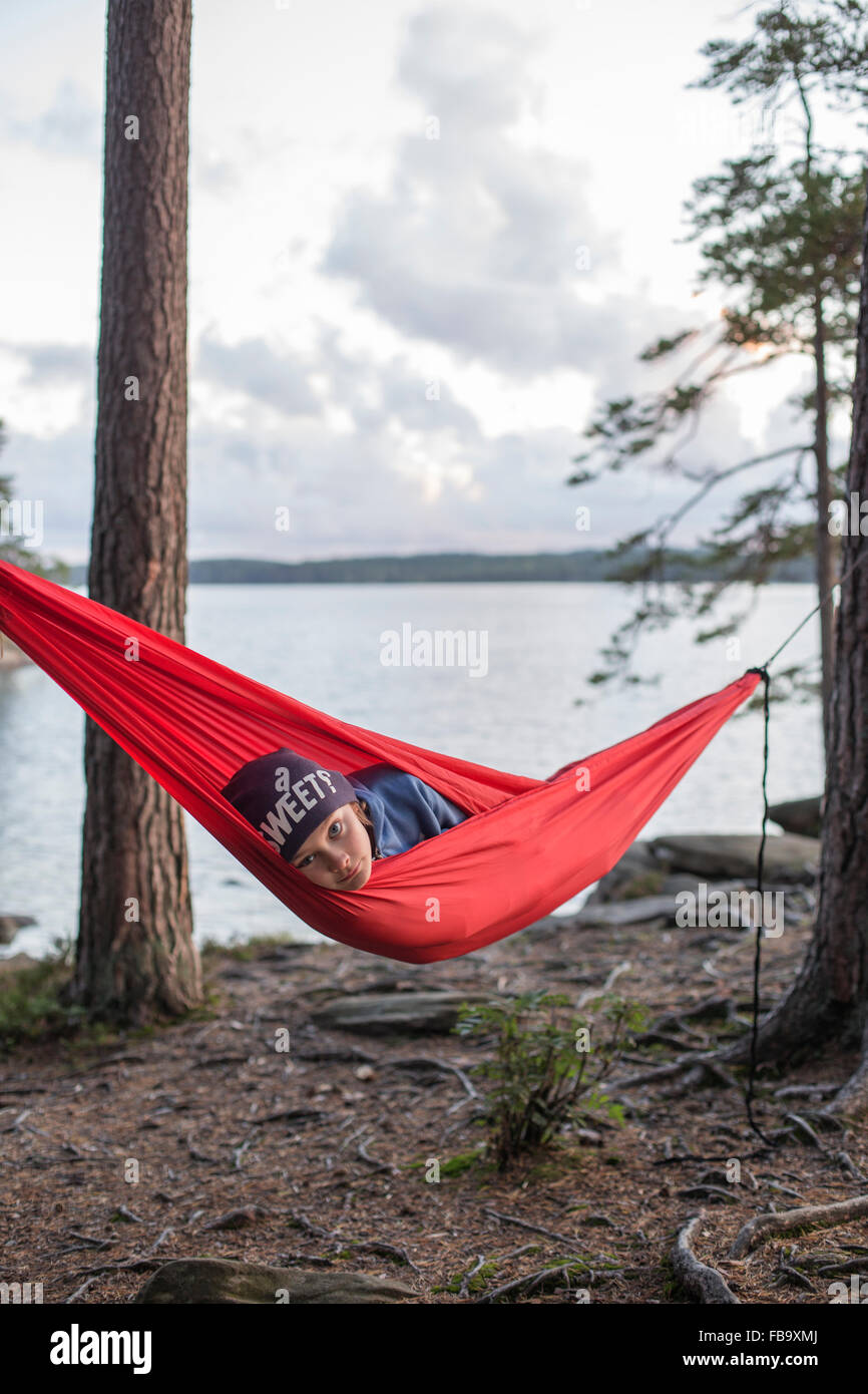 Suecia, Vastergotland, Lerum, Boy (12-13) acostado en la hamaca en el lago al atardecer Harsjon Foto de stock