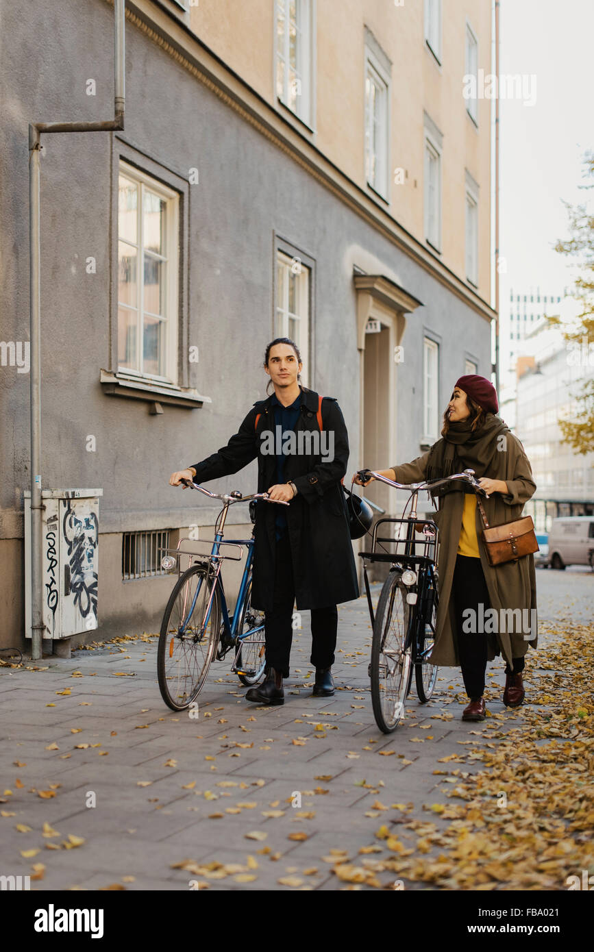 Uppland Suecia, Estocolmo, Vasastan, dos personas caminando con bicicletas Foto de stock