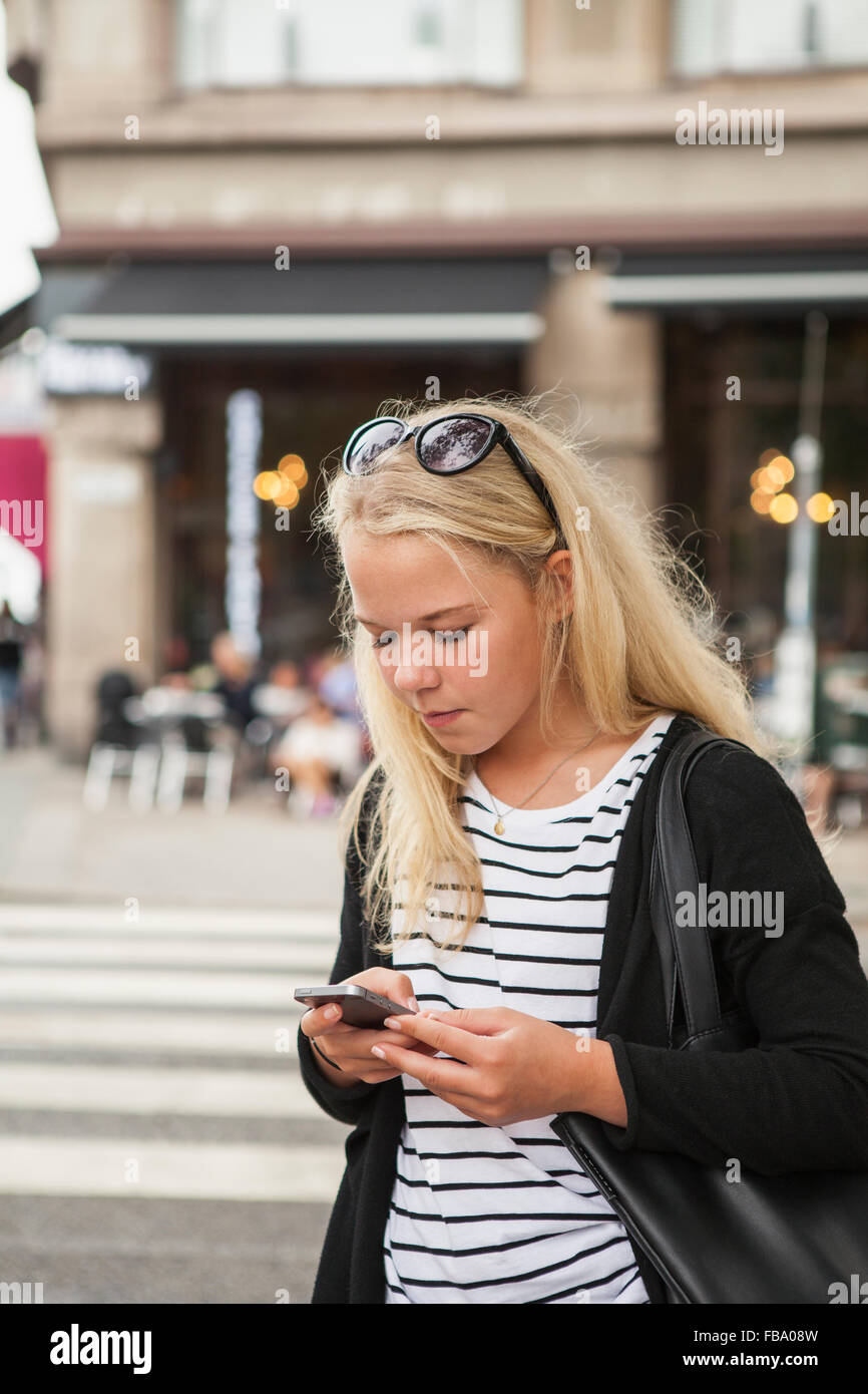 Suecia, Skane, Malmo, adolescente (14-15) usando el teléfono inteligente en la calle Foto de stock