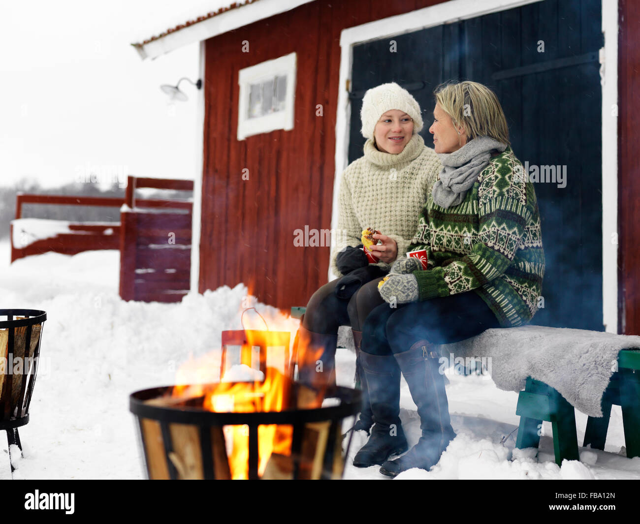 Suecia, hablando con la madre adolescente (14-15) en un banco en invierno Foto de stock