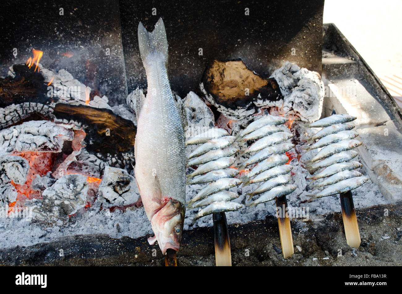 Filas de anchoas y sardinas en pinchos de madera cocinar en una barbacoa en  la playa playa de la Venus de Marbella Fotografía de stock - Alamy