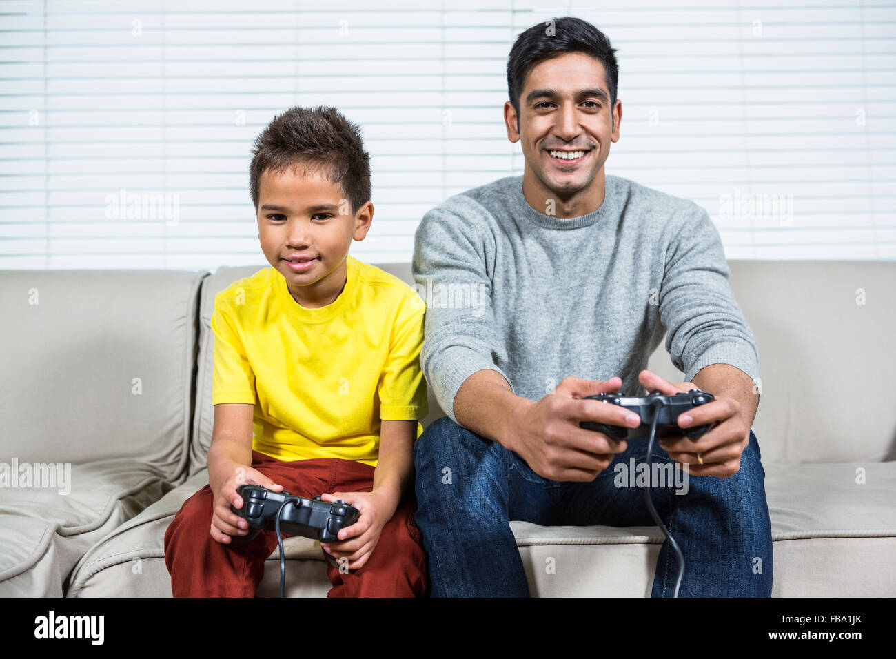 Padre e hijo jugar video juegos en el sofá Foto de stock
