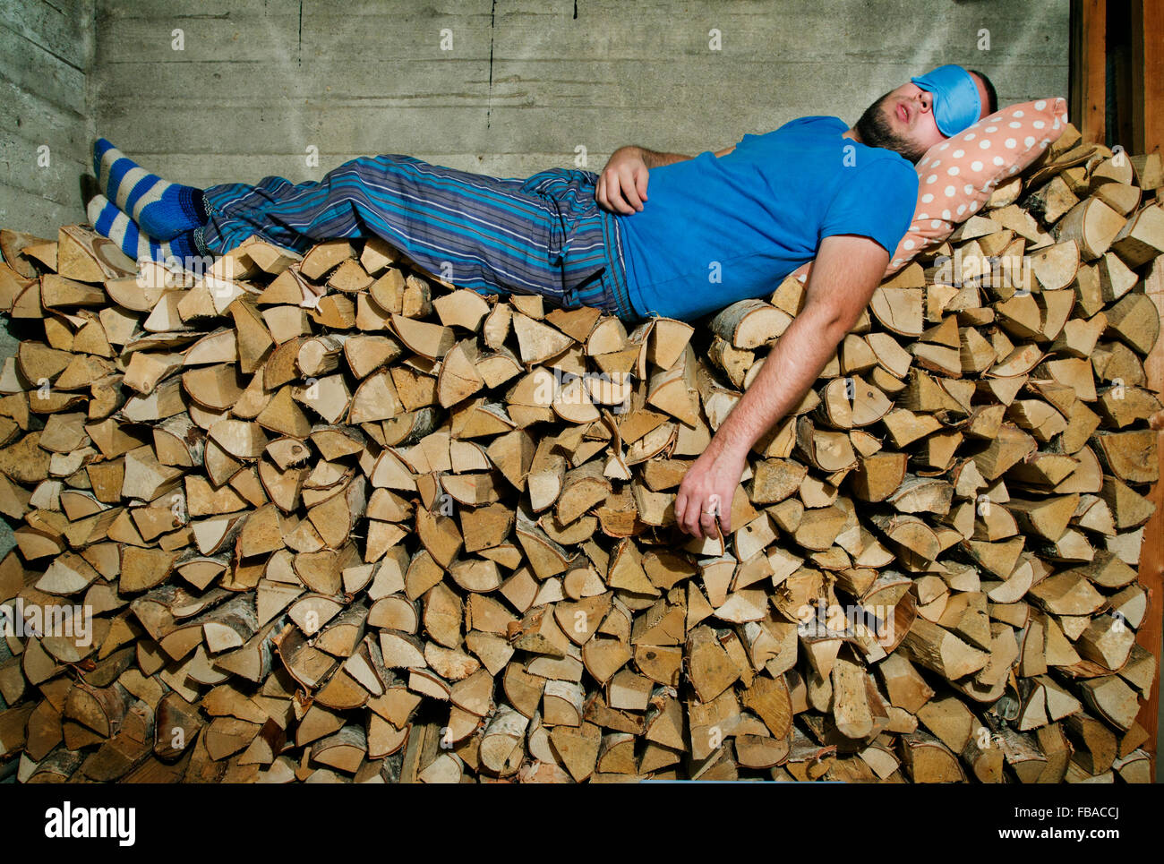 Finlandia, Heinola, hombre dormido sobre la pila de leña Foto de stock