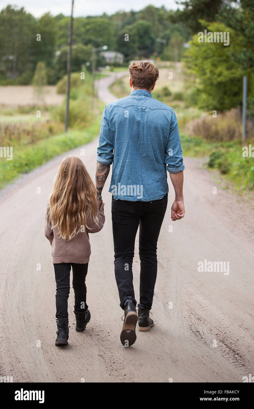 Finlandia, Uusimaa, Raasepori, Karjaa, Padre caminando con su hija (6-7) a lo largo de country road Foto de stock
